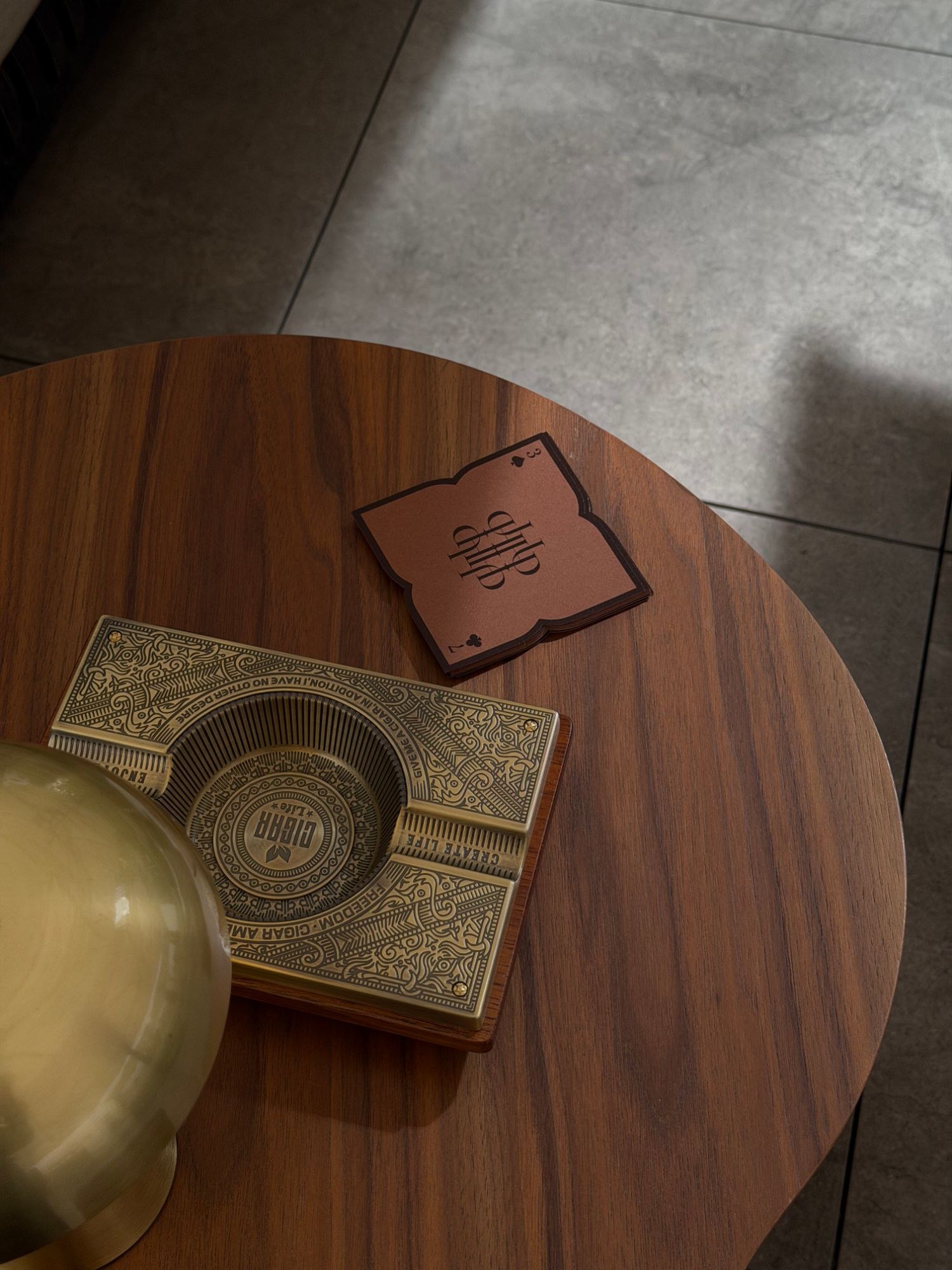 Brass ashtray and monogram coaster on walnut
